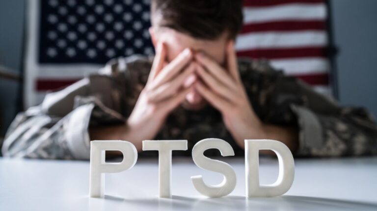 Veteran with Head in Hands and PTSD Letters in Front