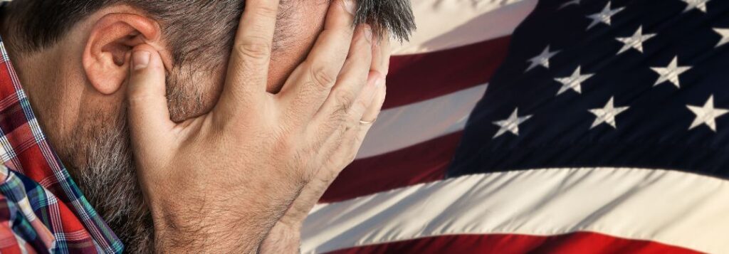 Veteran with His Head in His Hands and an American Flag Background