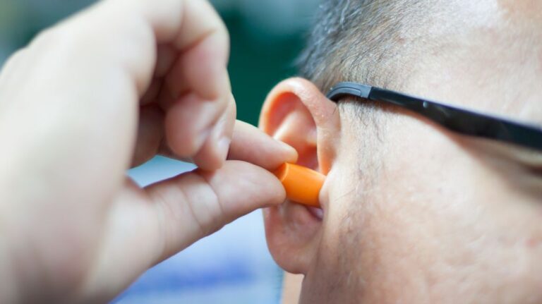 Man Putting in Orange Earplugs