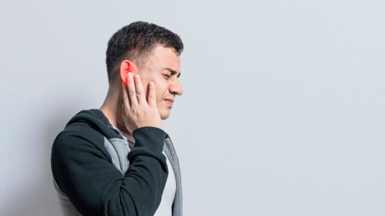 Man Holding his Red Ear Due to Tinnitus
