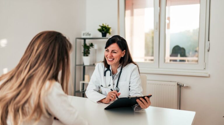 Female Doctor Talking to a Female Patient and Filling Out Paperwork