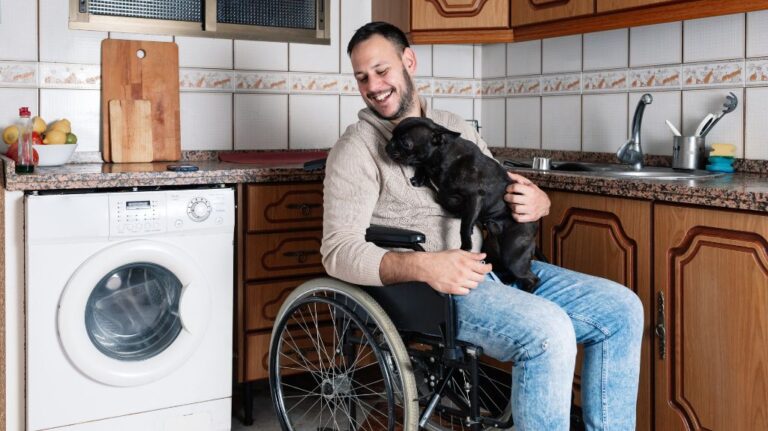 Veteran in a Wheelchair in a House with a Dog on His Lap