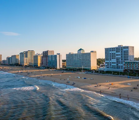 Virginia Beach scene featuring a sandy shore with a few people and several buildings in the background