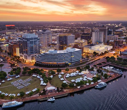 Norfolk city skyline featuring a harbor and a river, showcasing modern architecture against a clear blue sky