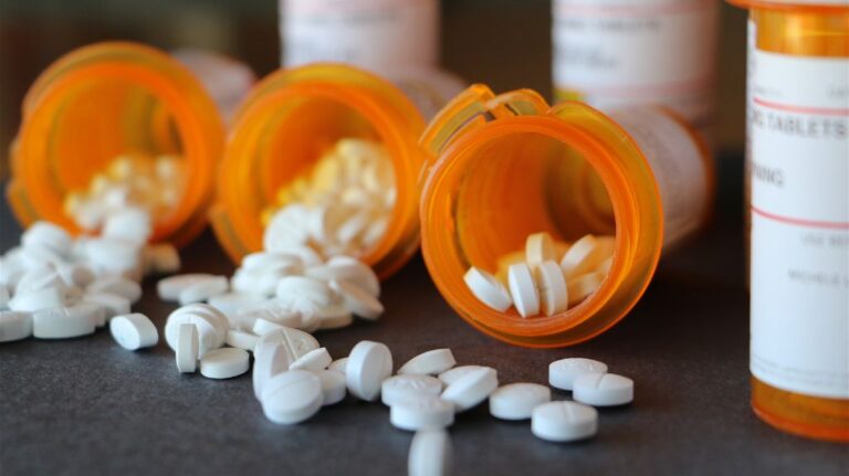 Bottles of Pills Spilling White Pills on a Table