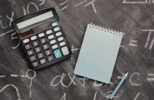 Calculator and Notepad on Black Chalkboard
