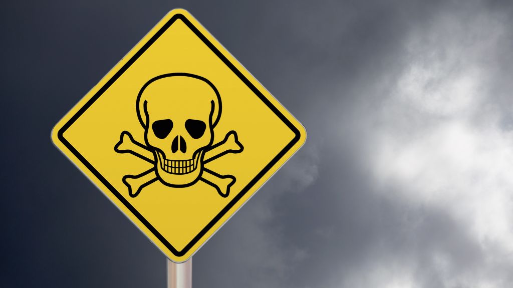 Yellow Toxic Sign with Skull and Cross Bones in Front of Stormy Sky