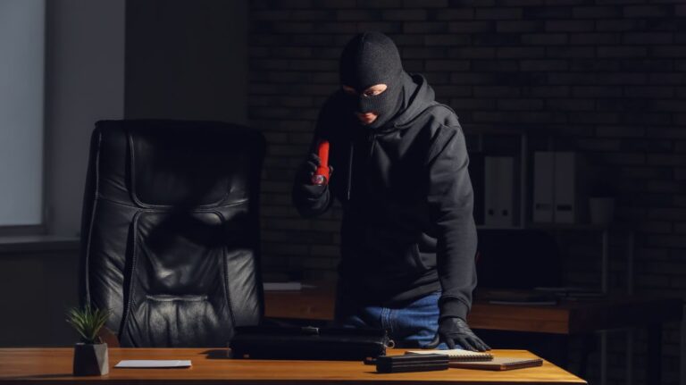 Thief with Flashlight Looking at a Desk in the Dark