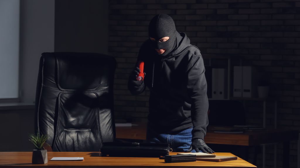 Thief with Flashlight Looking at a Desk in the Dark