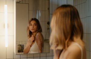 Woman Looking in Mirror with Major Scar Tissue on Her Arm