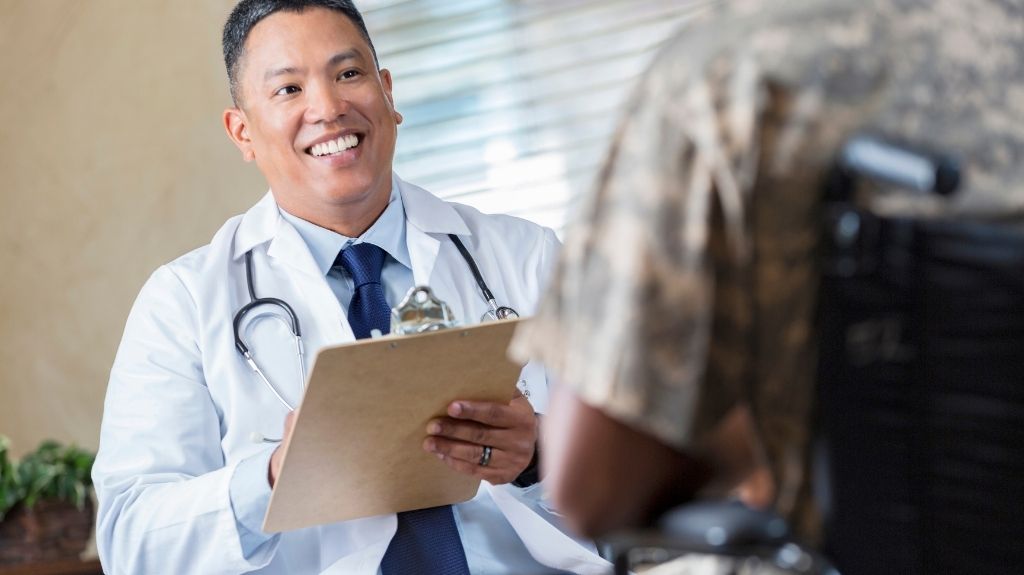 Veteran in Wheelchair Talking to Doctor with Clipboard
