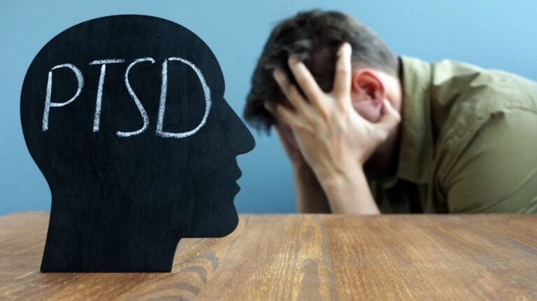 Man Holding Head in Hands with Black Head Cutout with PTSD Text