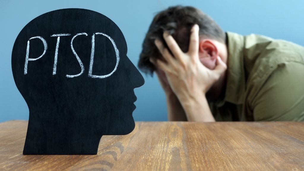 Man Holding Head in Hands with Black Head Cutout with PTSD Text