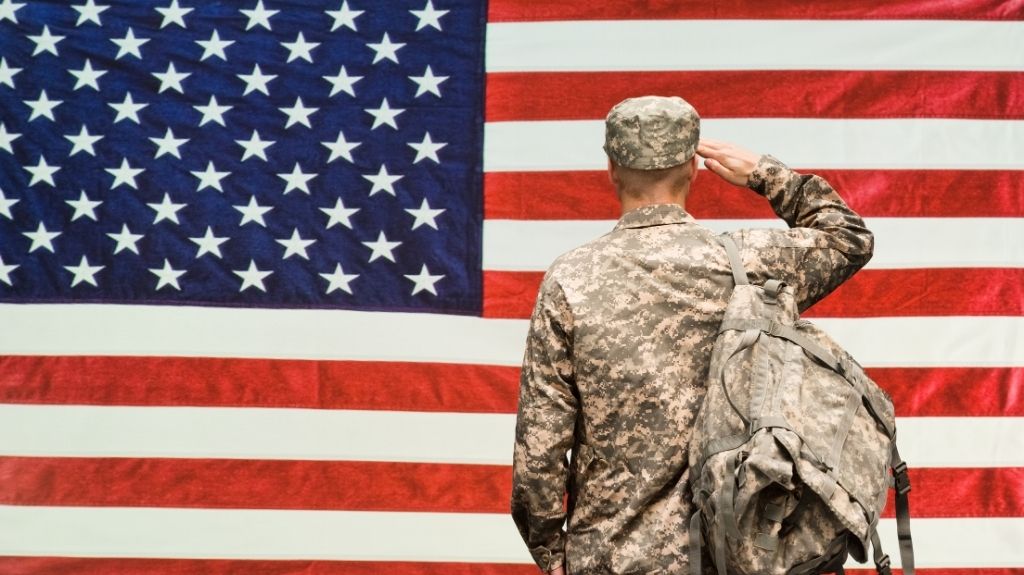 Soldier in Camouflage Saluting American Flag